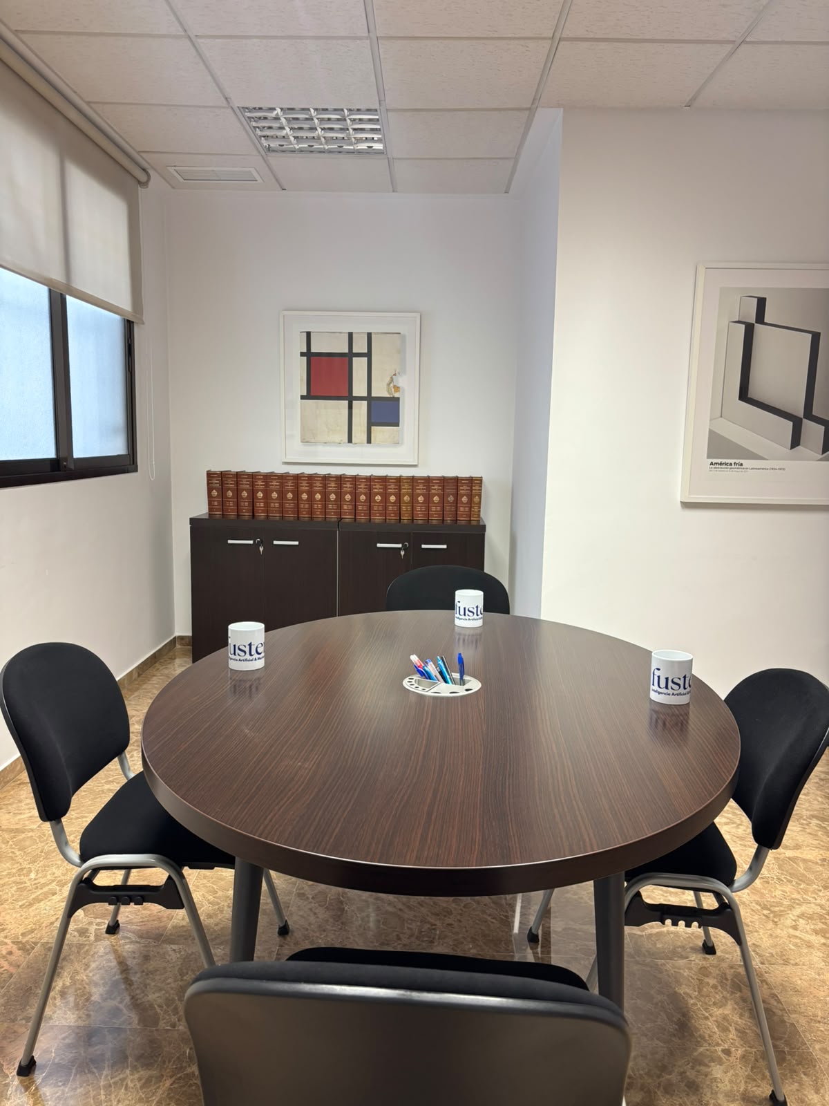 Sala de reuniones de la oficina de Fuster Agencia en Valencia con mesa redonda y tazas con el logotipo